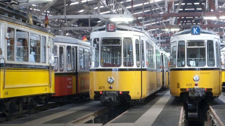 Mehrere alte Straßenbahnen in einer Abstellhalle.